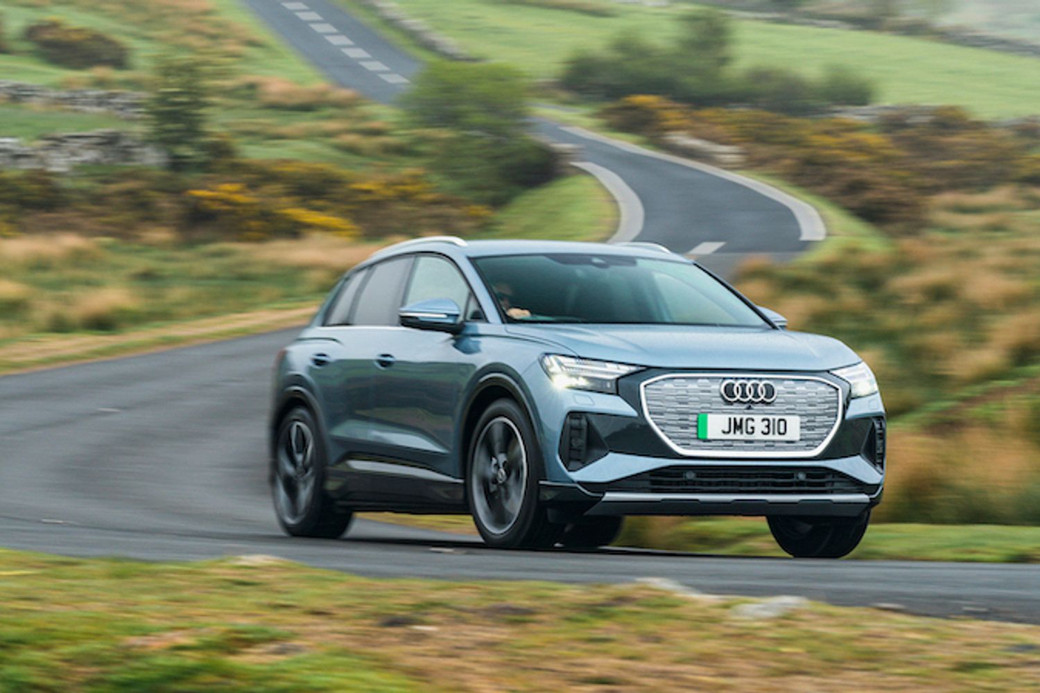 Audi Q4 e-tron front action shot, straight road in countryside, blue/silver car, RHD, UK plates