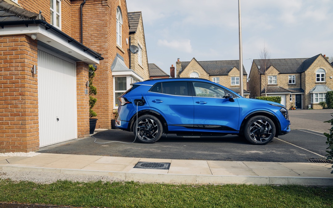Kia Sportage PHEV, blue, static side shot, parked and charging on driveway