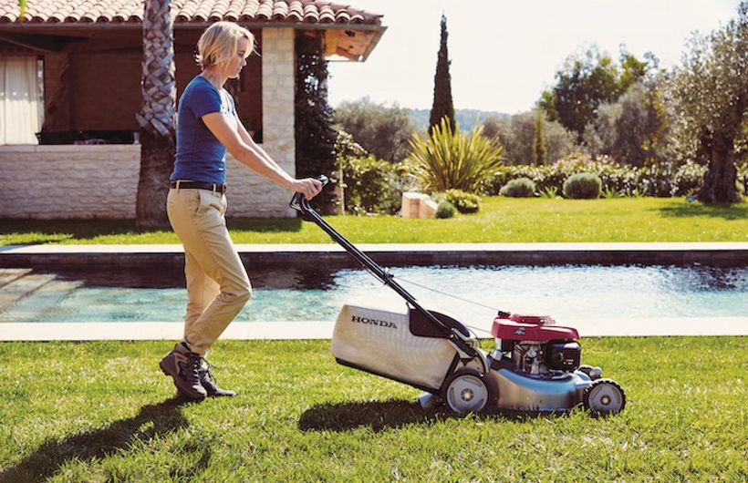 Honda petrol lawnmower with lady cutting grass